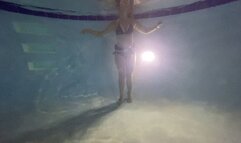 Underwater partial nudity in a public pool with old school weight belt and oval mask