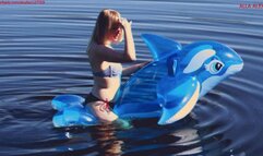 Alla has a hot ride on a transparent blue inflatable whale on the lake on a sunny day!!!