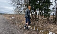 girl in short high-heeled boots walks through deep mud and puddles looking for a way home