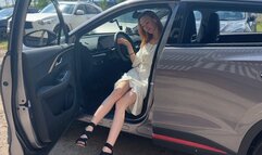 A girl in high-heeled shoes presses the pedals of her car and enjoys the sounds of the car engine