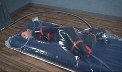 Bondage with red ropes of a special agent in a vacuum bag on an air mattress