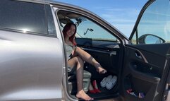 The girl plays in the car with shoes and feet, she touches everything with her feet, strokes the steering wheel with her heels