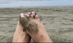 Feet in the sand in front of the sea