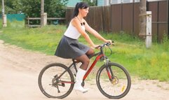 Pretty girl in high heels riding a bike and watering flowers