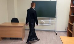 The teacher at school is preparing for the lesson and checking her notebooks, she is a little bored, so she plays with shoes sitting right in the classroom