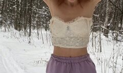 A girl in a terrible frost stands in the forest in ballet flats, shorts and a top and shakes from the cold