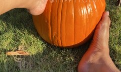 Tiippy is barefoot on the sidewalk stomping around and playing with a pumpkin with her feet