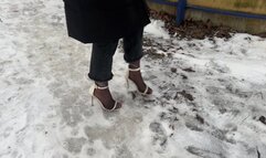 A girl in high-heeled shoes with open toes went out for a walk in winter, her heels are sliding on the ice and she is always slipping