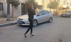 A girl in high-heeled shoes was waiting for her friend at her house and talking on the phone, not noticing the car that crushed her foot and shoe