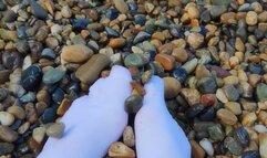 Playing with my feet in white socks with pebbles on the beach
