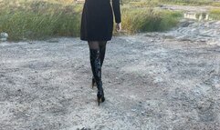 girl in high-heeled leather boots walks through the swamp, her boots get wet