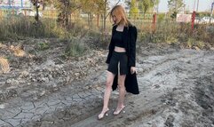 girl in mules in high heels walks through the mud and gets her feet dirty