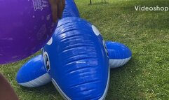 2 girls popping balloons on an inflatable whale