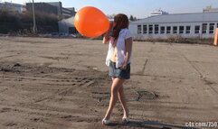 Titi blowing giant orange balloon outdoors (4K quality)