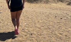 a girl in a short dress pees in the sand with foam on the beach